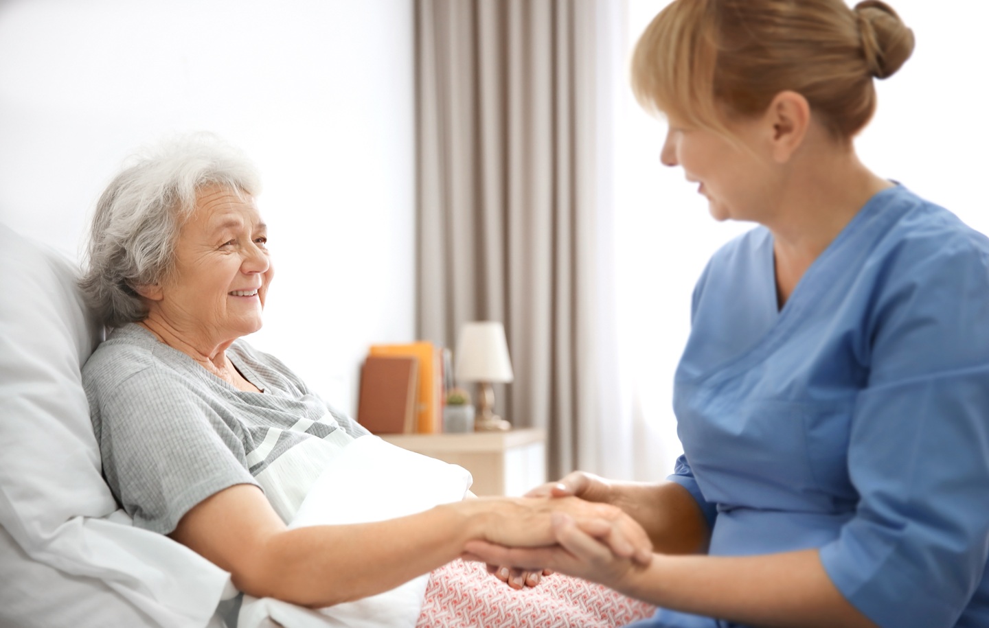 Pielęgniarka trzymająca dłoń pacjentki w domu